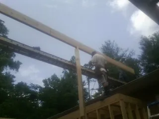 Carpenter setting a ridge beam over a new addition frame — Ice Dam Removal by Roofing Brothers in Ankeny