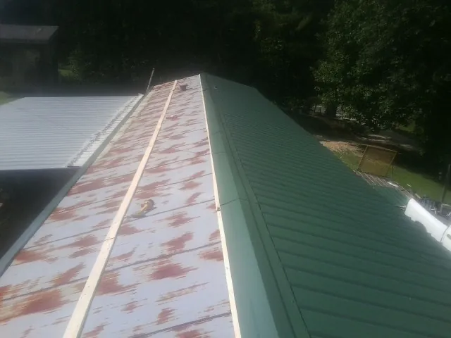 Old rusted panels beside newly installed green metal roofing — Wind Damage Roof Repair by Roofing Brothers in Ankeny