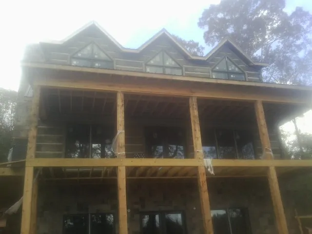 Dormers and porch framing on a large log home under construction — Roof Coating work by our crew in Ankeny
