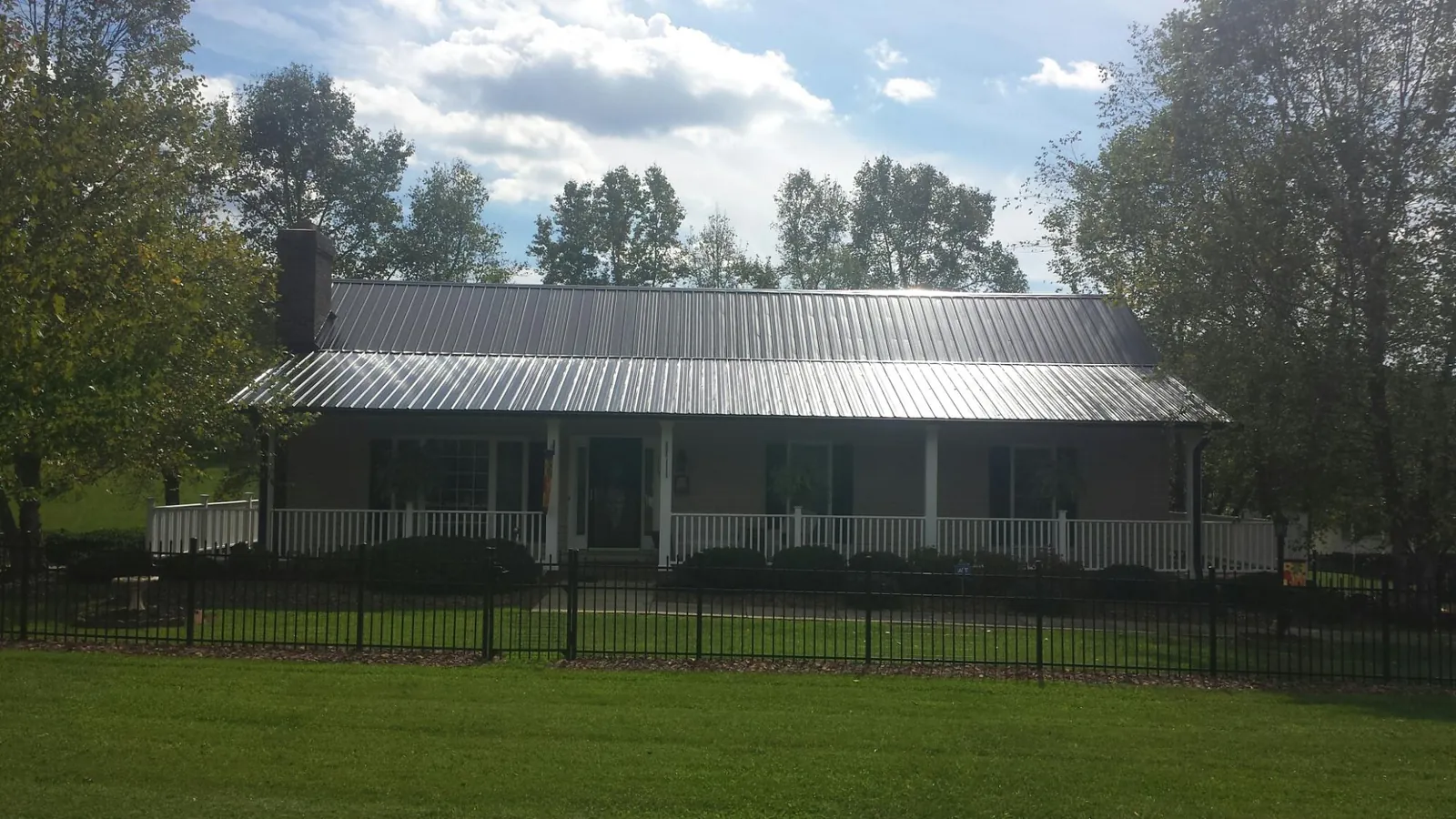 Gray metal roof on a brick ranch with a full width front porch — Gutter Guard Installation work by our crew in Ankeny