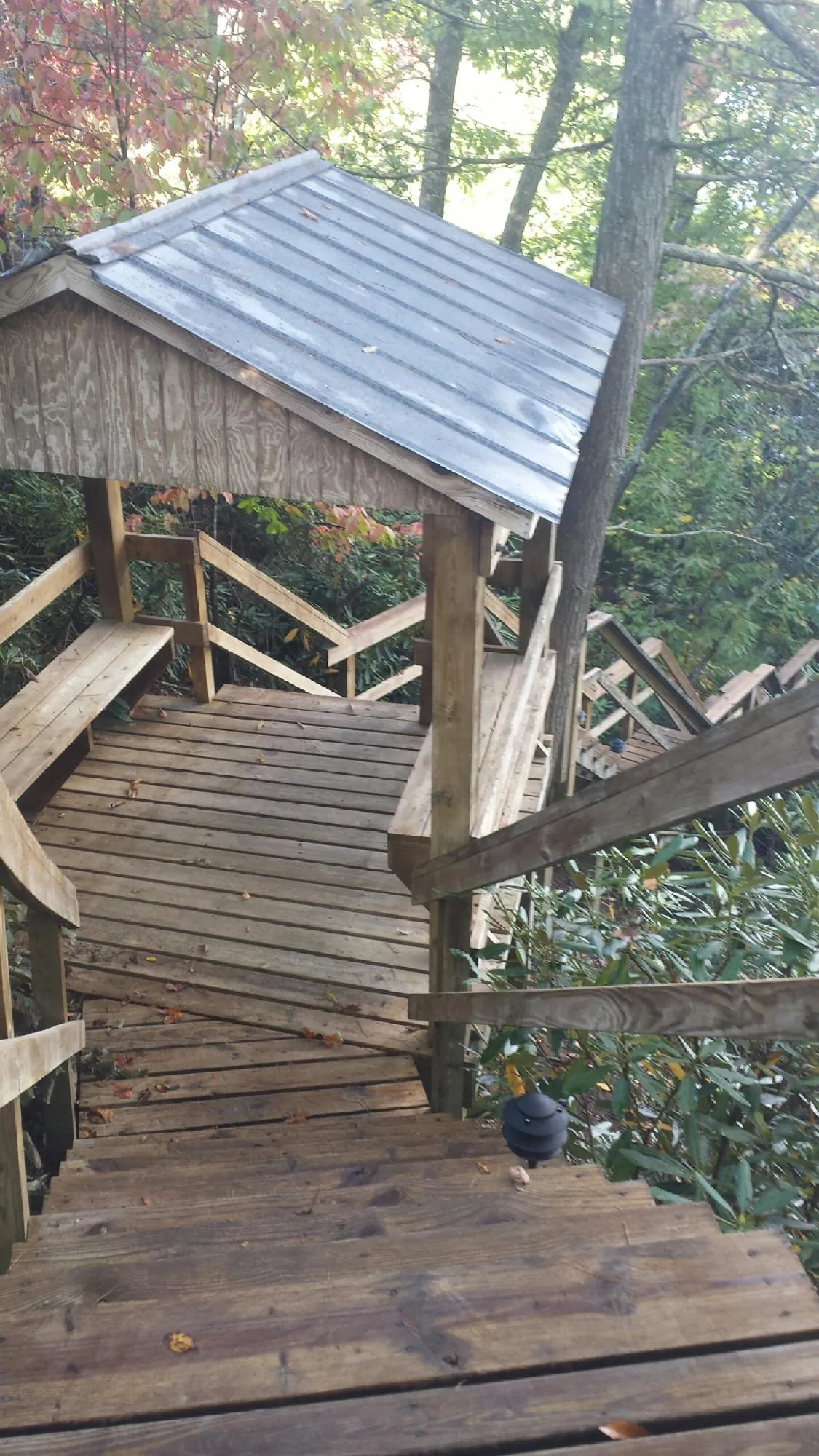 Metal roofed shelter over wooden steps on a wooded walkway — Skylight Repair & Installation work by our crew in Ankeny