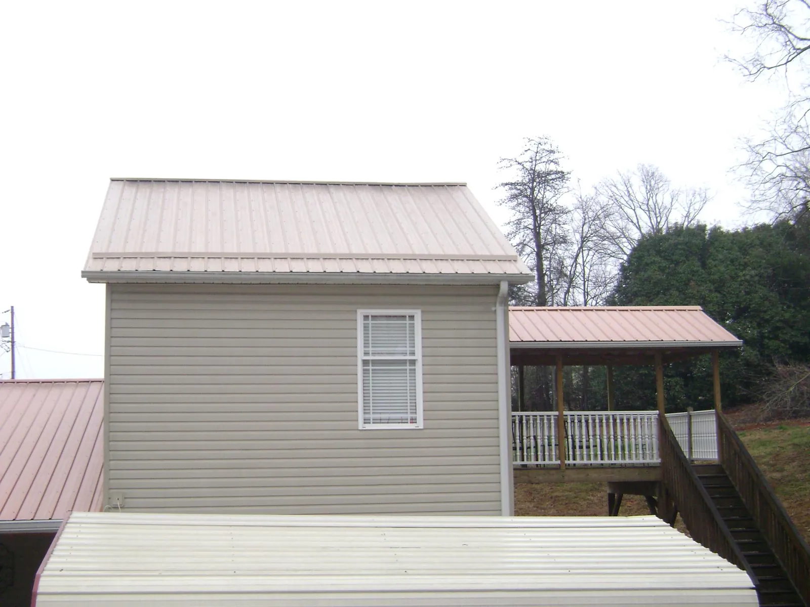 Tan metal roofs on a two story addition and attached porch, from a Roof Replacement job in Ankeny